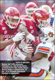  ?? PHOTO BY BEN GOFF ?? Mataio Soli (left), Arkansas defensive end, and De’Jon Harris, Arkansas linebacker, tackle Shaun Shivers, Auburn running back, on Oct. 19 at Reynolds Razorback Stadium in Fayettevil­le.