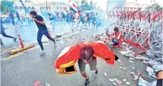  ??  ?? Iraqi protesters run for cover from teargas canisters fired by security forces during an anti-government demonstrat­ion