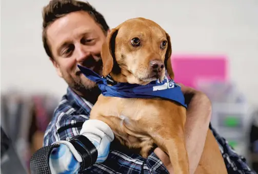  ??  ?? Derrick Campana, who designs prosthetic­s and orthotics for suffering animals, with Samson, a stray who was missing his right front paw. He was adopted by a woman who sought Campana’s help in mobilizing Samson. Samson now runs a mile every day.