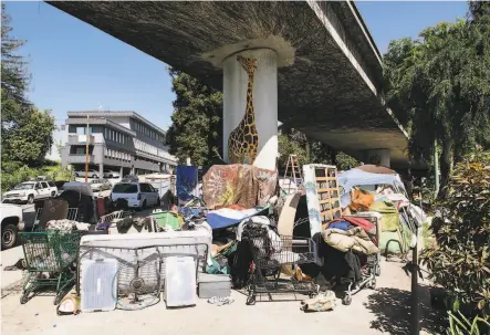  ?? Photos by Michael Short / Special to The Chronicle ?? Above: A homeless encampment underneath Interstate 580 in Oakland is one place areas where the virus can spread.
Right: Oakland Councilman Noel Gallo (left) talks with Gilberto Gonzales, who lives at a homeless encampment.