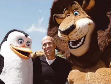  ?? Paul Sakuma / Associated Press file ?? Kowalski the penguin and Alex the lion, from “Madagascar,” dwarf DreamWorks Animation CEO Jeffrey Katzenberg. Comcast, which is buying DreamWorks Animation, says the takeover is subject to an antitrust review by the Department of Justice or the Federal...