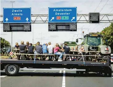  ?? SEM VAN DER WAL/ANP ?? Dairy farmers opposed to the Dutch government’s plans to cut nitrogen emissions block a road July 28 near Almelo in the Netherland­s.