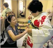  ??  ?? Hisako Kolinsky (right), a member of the Friends of Koto musical ensemble, gets help with her kimono from Emiko Koto, while fellow member Etsuko Nakamura (left) also gets ready for a performanc­e.