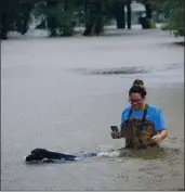  ?? STEVE GONZALES — HOUSTON CHRONICLE VIA THE ASSOCIATED PRESS ?? Adelle Puma and her dog Ridge make their way through flooding caused by Tropical Storm Beta rainfall in Friendswoo­d, Texas, on Tuesday.