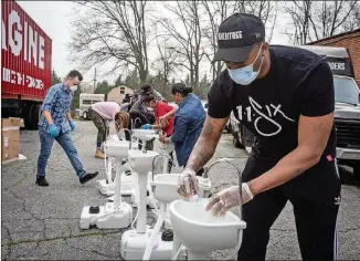  ?? AP PHOTO/ RON HARRIS ?? Hip-hop recording artist Lecrae assembles a portable washing station on March 19 in College Park. Lecrae reached out to Love Beyond Walls, a nonprofit led by Terence Lester, to offer assistance, and he donated money for the first 15 washing stations, which are for the use of homeless people in the Atlanta area.