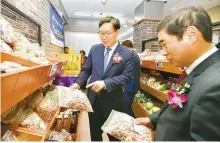  ?? Courtesy of NongHyup Bank ?? NongHyup Bank CEO Lee Dae-hoon, left, looks at items sold at the lender’s second branch that opened inside a NongHyup Hanaro Mart in Chuncheon, Gangwon Province, Nov. 14.