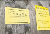  ??  ?? Warning signs mark the section of the SHW Casting buildng that suffered a collapsed roof in 2017 in Ansonia. The city of Ansonia is close to securing $ 400,000 to demolish a portion of the building.