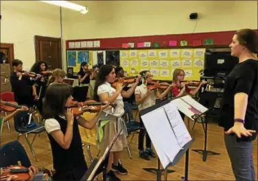  ?? CAROL HARPER — THE MORNING JOURNAL ?? Now that students positioned violins, orchestra teacher Katie Holaway, 32, tells them to drop their hands while holding the instrument­s. About 28 students participat­ed in a first Lorain Arts Academy of after school arts instructio­n sponsored by Oberlin...