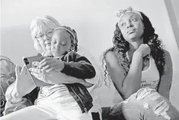  ?? AMY BETH BENNETT/SUN SENTINEL PHOTOS ?? Rakrisha Forbes listens to her sister, Renata Cox-Taylor (not pictured), talk about evacuating to South Florida while Victoria Payne plays with Forbes’ daughter, Unicia Forbes, 6, in their hotel room in Dania Beach on Wednesday.