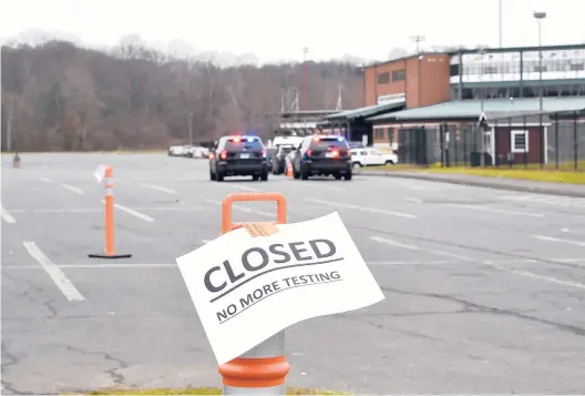  ?? JESSICA HILL PHOTOS/SPECIAL TO THE COURANT ?? Police vehicles bring up the rear of a line of cars containing drivers and passengers waiting to be tested Monday at the state COVID-19 testing site at Veterans Memorial Stadium in New Britain.