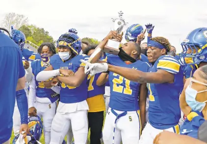  ?? JONATHON GRUENKE/STAFF ?? Marqaz Young kisses the trophy as he and Oscar Smith teammates celebrate the Class 6 Region A championsh­ip after defeating Thomas Dale 49-3 Saturday in Chesapeake.