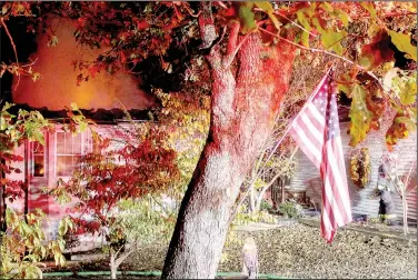  ?? (NWA Democrat-Gazette/Keith Bryant) ?? Vista Battalion Chief Ronnie Crupper (right, background) exits a Moors Lane home that caught fire Oct. 1.