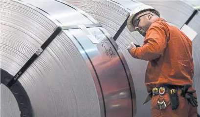  ?? TARA WALTON/CANADIAN PRESS FILE PHOTO ?? A Dofasco employee examines rolls of steel in Hamilton. ADF Group Inc. has cut employee hours at its Terrebonne plant in Quebec.