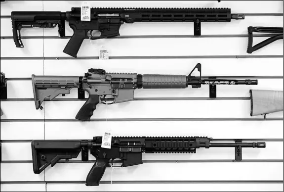  ?? ELAINE THOMPSON / AP FILE (2017) ?? A Ruger AR-15 semi-automatic rifle, center,, sits on display with other rifles on a wall in a gun shop in Lynnwood, Wash. The weapon has been favored by mass-shooters in Newtown, Conn.; San Bernardino, Calif.; Las Vegas and, earlier this month,...