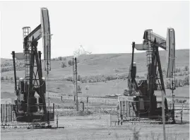  ?? [AP FILE PHOTO] ?? Oil pumps and natural gas burn off in Watford City, N.D.