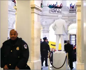  ?? The Associated Press ?? With a sign hanging above that says DACA Si, Trump No Capitol Police hold their posts as people participat­e in civil disobedien­ce in support of the Deferred Action for Childhood Arrivals (DACA) program, in the Russell Rotunda, Wednesday.