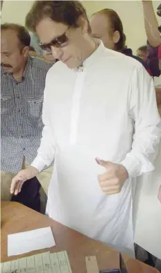  ?? — AFP ?? Imran Khan, head of the Pakistan Tehreek-e-insaf party, gives a thumb impression as he casts his vote at a polling station during the general election in Islamabad on Wednesday.