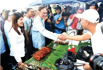  ??  ?? Anwar (centre) accompanie­d by Vivian (second le ) and Christina greets Mohd Arben Harith during a visit to the Sandakan Ramadan Bazaar yesterday.