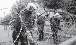  ?? REUTERS ?? Polish members of the NATO-LED Kosovo Force (KFOR) set up wire fencing as they stand guard near a municipal office in Zvecan, Kosovo, May 31.