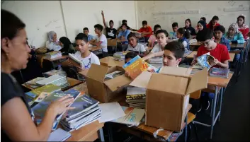  ??  ?? Palestinia­n refugee students receive new studying books inside their classroom, during the first day of a new school year, at one of the UNRWA schools, in Beirut, Lebanon, on Monday. AP PhoTo/huSSeIn MAllA
