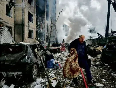  ?? KOSTIANTYN LIBEROV/LIBKOS/GETTY IMAGES ?? A resident carried his belongings through the debris after a rocket hit an apartment building in the center of Kyiv on Tuesday.