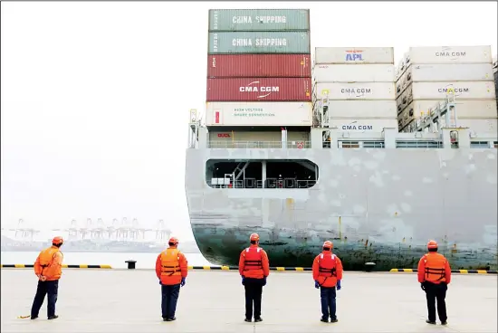  ?? (AP) ?? In this file photo, workers watch a container ship arrive at a port in Qingdao in east China’s Shandong province. Factories across China are still closed to try to limit spread of the coronaviru­s,
leaving business owners in limbo.