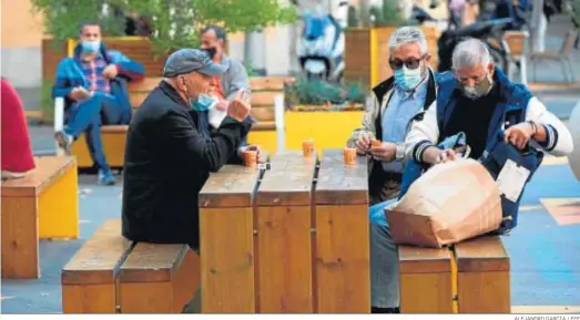  ?? ALEJANDRO GARCÍA / EFE ?? Varias personas almorzando en un banco de una calle del centro de Barcelona.