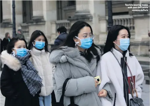  ??  ?? Tourists wearing masks walk past the Louvre
museum in Paris