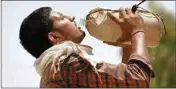  ?? PIC/PTI ?? A labourer drinks water at a grain market on a hot summer day as temperatur­e reached 48 degrees Celsius, in Bikaner