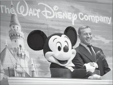  ?? Drew Angerer Getty Images ?? COMCAST last week bid $65 billion for much of Rupert Murdoch’s Fox, which had already agreed to be sold to Disney. Above, Disney chief Bob Iger and Mickey Mouse at the New York Stock Exchange in November.