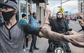  ?? Robert Gauthier Los Angeles Times ?? PROTESTERS keep potential looters from entering a Hollywood store. Many politician­s have been blaming violence in their cities mostly on outside agitators.