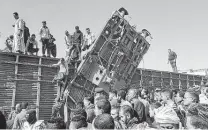  ?? Mahmoud Maqboul / DPA / TNS ?? People gather to inspect the damage after a passenger train was rear-ended by another locomotive near Tahta, Egypt.