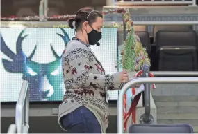  ??  ?? Kate Ulrich, director of live programmin­g and entertainm­ent, hangs up Christmas decoration­s at Fiserv Forum.