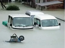  ??  ?? Acqua e vento Sopra, passanti si avventuran­o nel centro di Tokyo spazzato dal tifone Hagibis. A destra, auto sommerse dall’acqua nella cittadina di Ise, nel centro del Giappone. Sotto, il fiume Isuzu in piena per effetto del ciclone, il più devastante da 60 anni