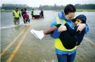  ?? AFP ?? FLEEING FROM FLORENCE: Volunteers help rescue three children from their flooded home in James City on Friday. —