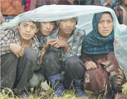  ?? WALLY SANTANA/THE ASSOCIATED PRESS ?? Villagers wait in the rain Wednesday as an aid relief helicopter lands at their remote mountain village of Gumda, near the epicentre of Saturday’s massive earthquake in the Gorkha District of Nepal. Around eight million Nepalese have been affected by...