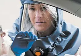  ?? RICK BOWMER/AP ?? Lee Cherie Booth performs a coronaviru­s test Friday outside the Salt Lake County Health Department in Utah. At least seven states reported record virus case numbers Saturday.