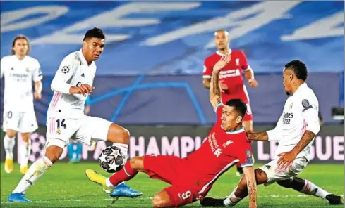 ?? AFP ?? Liverpool’s midfielder Roberto Firmino (centre) challenges Real Madrid’s midfielder Casemiro (left) during the UEFA Champions League first leg quarter-final football match on Tuesday.