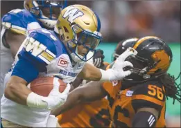  ?? The Canadian Press ?? Winnipeg Blue Bombers running back Andrew Harris, left, stiff-arms B.C. Lions linebacker Solomon Elimimian during the first half of Friday’s game.