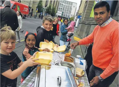  ?? Picture: Dougie Nicolson. ?? Praveen Kumar, owner of the Tabla Indian Restaurant, dishing out curry to Emily Hunter-Bell, Tanvi Kumar and Josh Ferris, for a donation, as part of World Food Day in Perth city centre yesterday.