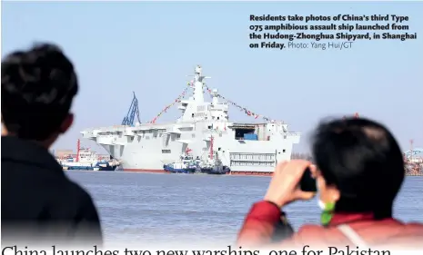  ?? Photo: Yang Hui/GT ?? Residents take photos of China’s third Type 075 amphibious assault ship launched from the Hudong-Zhonghua Shipyard, in Shanghai on Friday.