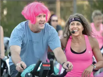  ?? Dan Watson/The Signal ?? Event coordinato­r Janet Cheveres, right, pushes participan­t Rick Boggs, wearing a pink wig for Breast Cancer Awareness Month, during his two-hour ride at the annual Henry Mayo Ride for a Cure event, held Friday at Santa Clarita Athletic Club in Newhall.