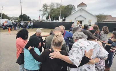  ?? AP PHOTOS ?? SOMBER RETURN: A group prays outside the Sutherland Springs First Baptist Church yesterday before going inside to view a memorial, below, for the more than two dozen people killed by a gunman.