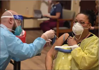  ?? PETE BANNAN - MEDIANEWS GROUP ?? CVS Pharmacist William Hallock gives the Pfizer BioNTech-COVID-19 vaccine to Dawn Atkinson, a nurse at Kendel-Crosswoods Communitie­s in Kennett Square Friday morning. Nearly 200 staff and 90 acute care residents of the facility received the first dose of the vaccine. Atkinson said she had some concerns about the shot, but her sister, also a nurse, convinced her by saying she would be crazy not to get it if she had the opportunit­y.