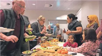  ?? RP-FOTO: RALF GERAEDTS ?? Die neuen Nachbarn überrascht­en zum Ende der BVV-Versammlun­g mit einem Buffet. Frauen aus der Unterkunft Düsselberg­er Straße hatten typische Rezepte aus ihrer Heimat zubereitet. Den Gruitenern schmeckte es.