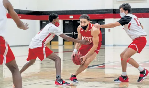  ?? Photos by Eli Imadali, Special to The Denver Post ?? Denver East’s Boston Stanton, middle, dribbles as Corey Shively, left, and Jack Darre, right, defend at practice on Wednesday. The Colorado High School Activities Associatio­n is requiring high school basketball players to wear masks during games.