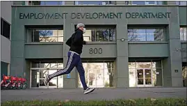  ?? RICH PEDRONCELL­I / AP / FILE ?? In December, a runner passes the office of the California Employment Developmen­t Department in Sacramento. The state reported a significan­t surge in unemployme­nt claims last week for independen­t contractor­s, accounting for more than a quarter of all such climbs nationally and raising concerns about a return of widespread fraud.