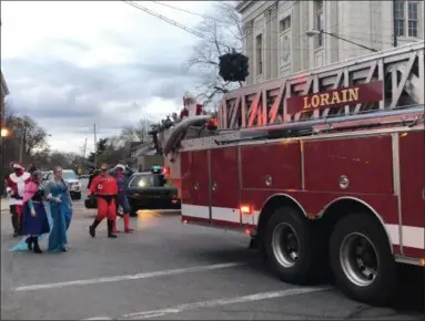  ?? BRIANA CONTRERAS — THE MORNING JOURNAL ?? Santa is carried into Lorain’s third annual Waterfront Winterfest at Veterans Park, West Erie Avenue, Nov. 25 on a Lorain Fire Department fire truck, followed by Holiday characters and super heroes from the Super Heroes To Kids in Ohio.