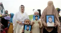  ?? AP ?? A Pashtun family from the tribal area displays pictures of a missing family member during a rally in Peshawar. —