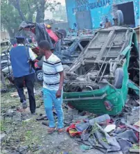  ?? — AFP ?? People stand among the damage at the scene of a blast after two car bombs exploded in Mogadishu on Saturday.